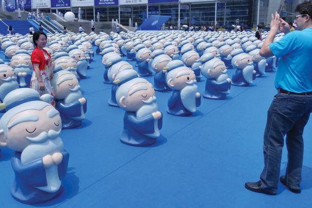 Person standing with a confucius display as a metaphor for Germany too dependent on Confucius Institutes