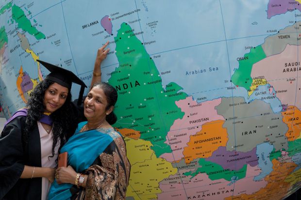 Graduate and lady pose for photograph infant of giant globe with graduate pointing to a place near India Graduate and lady pose for photograph infant of giant globe to illustrate Offer loans to turbocharge Indian recruitment, Johnson tells UK