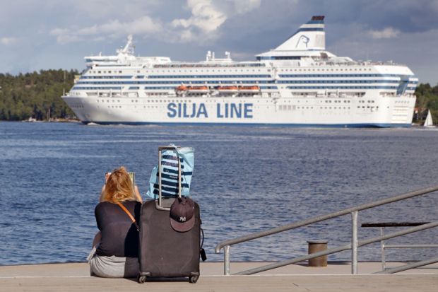 A woman is sitting on the quayside waiting for the boat with her luggage in  Lidingo, Sweden to illustrate Grant deadlines ‘create disparity’