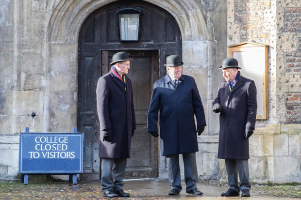 Entrance door shut with a sign reading 'College closed to visitors' at Trinity college at the University of Cambridge, England. Trinity college at the University of Cambridge, England. Men standing at closed door with sign reading 'College to to visitors' to illustrate Elitism cannot be fixed without Oxbridge admissions reform