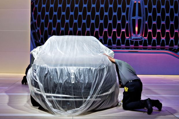 A worker cleans the wheel of a covered vehicle at the Ford Motor Co. Lincoln to illustrate University keeps details of record v-c payout under wraps