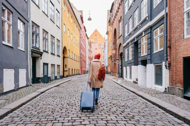 A woman walking down the street and pulling a suitcase to illustrate wanting to leave 