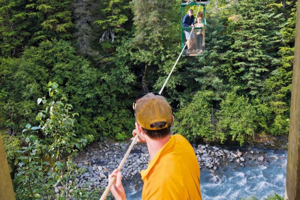 Man pulling hikers across the hand tram at Winner Creek Man pulling hikers across the hand tram at Winner Creek to illustrate US research funding emerges as election battleground