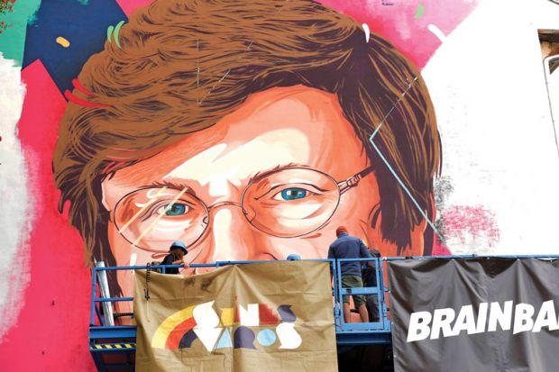 A painter makes finishing touches on a mural showing a portrait of Katalin Kariko as she is mentioned in the story