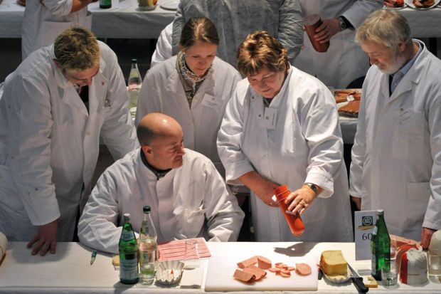 Food testers evaluate products during a quality check for ham and sausage as a metaphor for quality and control