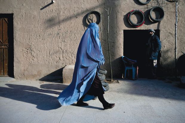 A woman wearing a burqa walks along a road at the Khwaja Koza Gar area in Herat A woman wearing a burqa walks along a road at the Khwaja Koza Gar area in Herat to illustrate Segregation and half-empty campuses as Afghan universities reopen