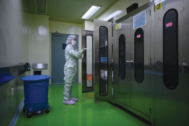 A lady putting on protective clothing required to enter a testing lab