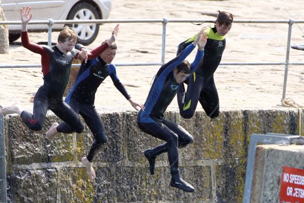Four people jumping off from a harbour wall. Four people jumping off from a harbour wall as a metaphor for cutting English fees and student numbers.