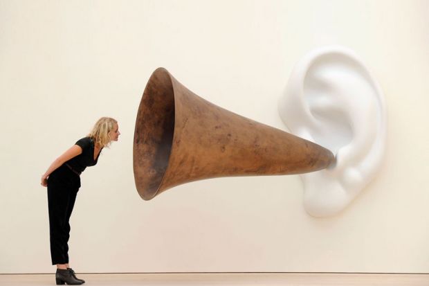 Woman leans in looking at an installation installation by US artist John Baldessari entitled ‘Beethoven’s Trumpet (With Ear)’ as a metaphor for universities will ‘listen to students’