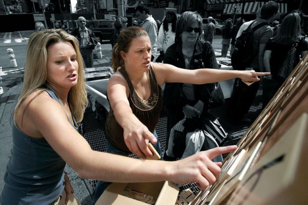 Two ladies pointing at a giant Sudoku in the street as a metaphor for problem solving.