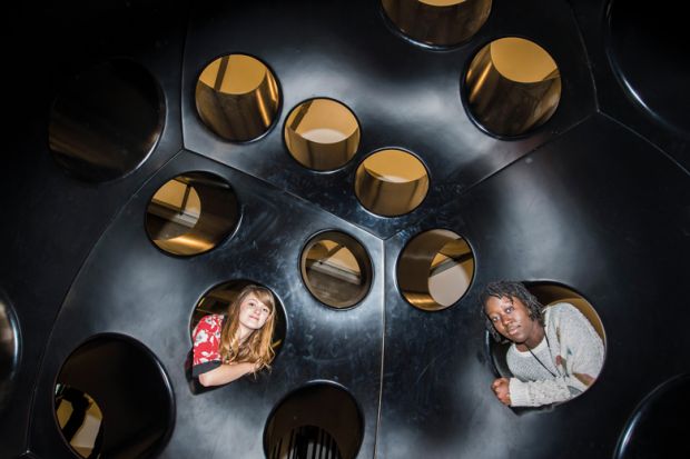 Two people looking inside holes in an immersive art installation in London, UK Two people looking inside holes in an immersive art installation in London, UK_to illustrate Academics urged to fill policy void at heart of new UK government