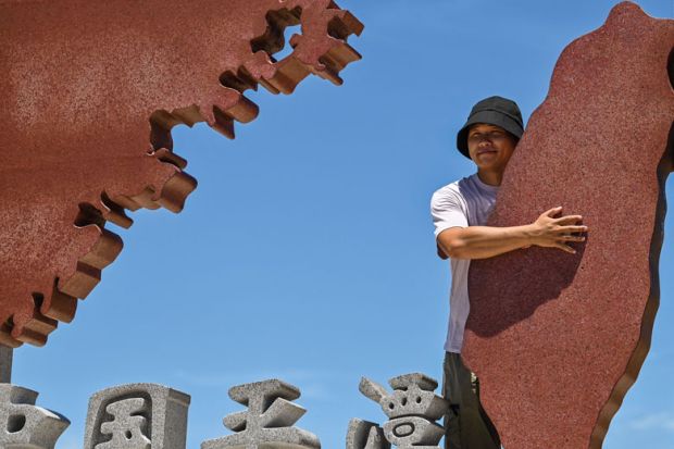 A tourist poses with a monument representing mainland China A tourist poses with a monument representing mainland China to illustrate Taiwan-Beijing tensions ‘could rattle international students’