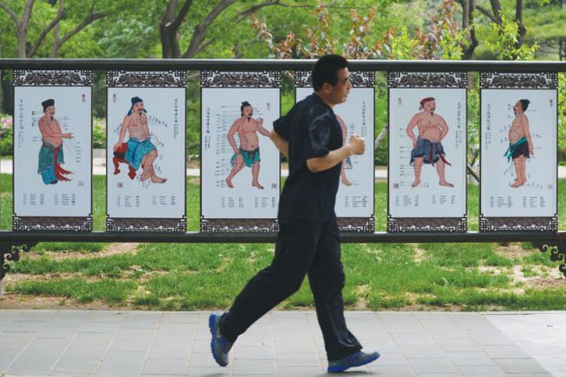 A man runs past a billboard showing Chinese medicine at a park in Beijing A man runs past a billboard showing Chinese medicine at a park in Beijing as a metaphor for Hong Kong to give Chinese medicine thorough check-up