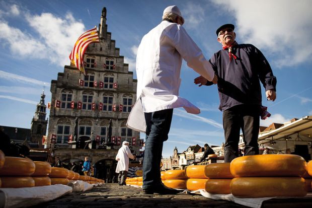Shaking hands with a Cheesemaker at a market at the opening of the Dutch Cheese season in Gouda Shaking hands with a Cheesemaker at a market at the opening of the Dutch Cheese season in Goudato illustrate UK universities near Elsevier deal after publisher drops price