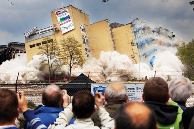 Residents watch a controlled demolition in the Netherlands Residents watch a controlled demolition in the Netherlands to illustrate Overseas student caps in limbo after Dutch government collapses