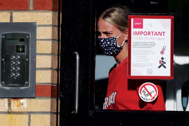 A student leaves one of the accommodation blocks with a Covid sign on the window