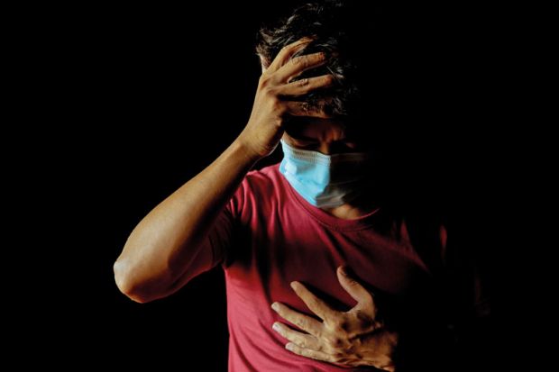 A man wearing a mask has a headache and has difficulty breathing after contracting Covid-19 even after undergoing treatment. Asian man wearing a mask has a headache and has difficulty breathing after contracting Covid-19 even after undergoing treatment. to illustrate long Covid