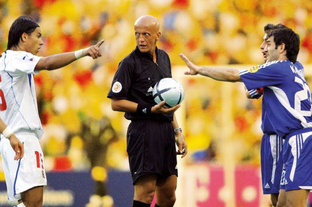 Footballers arguing with the referee in the centre to illustrate 