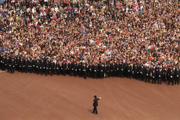 Well wishers surge along the Mall behind the police towards Buckingham Palace to celebrate the Royal Wedding of Prince William to illustrate Should student number caps be reinstated in England?