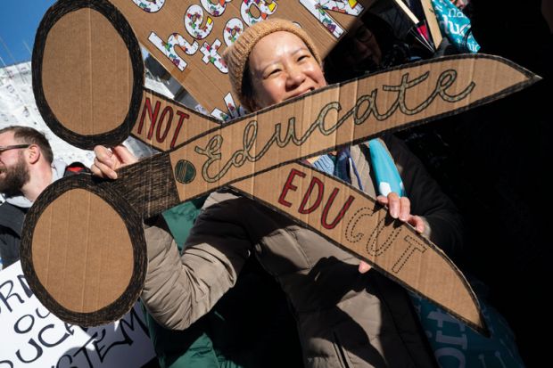 UCU member holding a cardboard banner of a pair of scissors to protest against cuts UCU member holding a cardboard banner of a pair of scissors to protest against cuts to illustrate UK sector at ‘rock bottom’ as pay dispute derails graduations