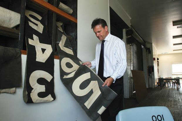 Man holding an old scoreboard as a metaphor for Staff counts are a numbers game