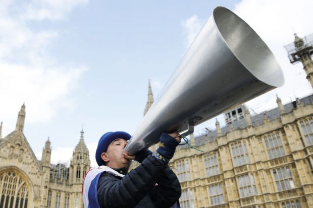 A demonstrator holds up a megaphone  near the Houses of Parliament to illustrate the Free speech bill fans urge ministers to force home right to sue