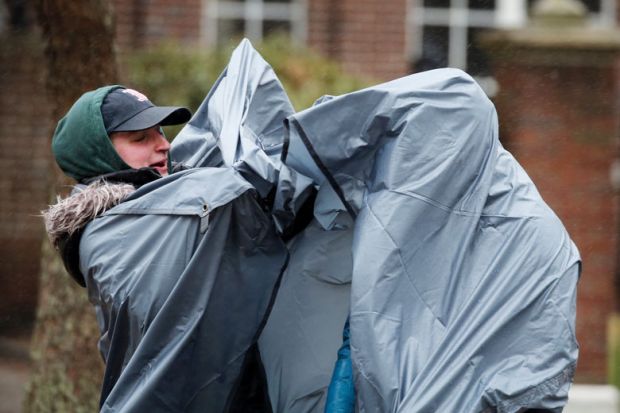 Spectators struggle with the elements while waiting  to illustrate edX sale to 2U leaves both  sides struggling