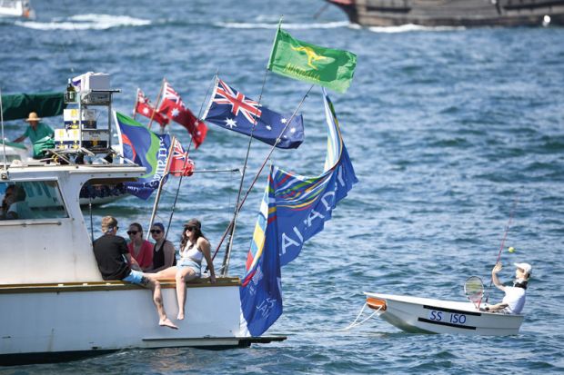 A small boat is being towed on the harbour in Sydney, Australia by a larger boat with people relaxing on board A small boat is being towed on the harbour in Sydney, Australia by a large boat with people relaxing on board to illustrate the pay disparity data reveal elite clique in Australian universities