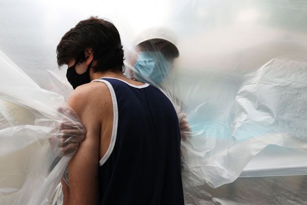John Sileo hugs his grandfather, Domenik Sileo through a plastic drop cloth hung up on a homemade clothes line during Memorial Day Weekend on May 24, 2020 in Wantagh, New York.