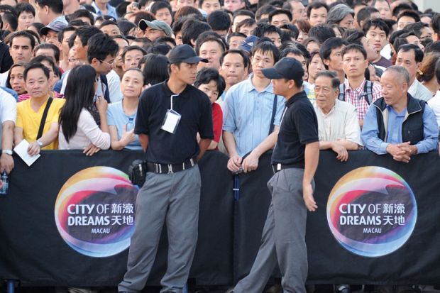 People wait for the opening of a new casino outside the City of Dreams complex in Macau to illustrate University of Macau edging us out, international academics fear