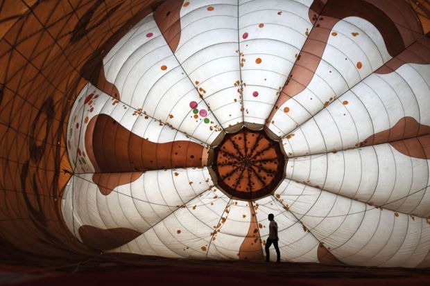  A pilot stretches a hot balloon air as it inflates to illustrate Pakistani universities close temporarily amid soaring inflation