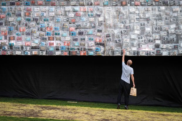 A visitor looks at a book on the side of the Big Ben Lying Down installation to illustrate Forget book deals if REF open access rules proceed, warn scholars