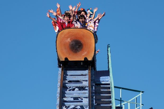 Japanese women ride a roller coaster at Toshimaen amusement park in Tokyo to illustrate Impact of Japanese international tuition fee hike debated