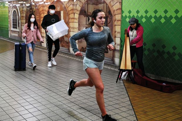 Student running by others wearing face masks to illustrate Splash overseas fee cash back on students, Australia urged