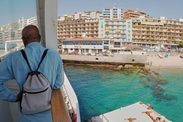 Man standing on ferry looking at Messina city skyline Man standing on ferry looking at Messina city skyline to illustrate Italy turns hotels into student halls to battle demographic decline