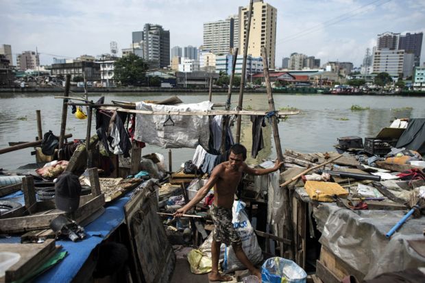 Worker collecting plastic bottles floating on the river at the banks of Pasig River in Manila to illustrate Philippines’ higher education ‘more unequal despite reforms’