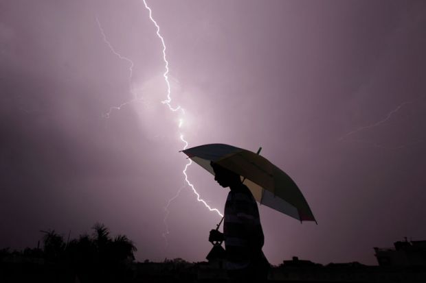 A pedestrian walks with an umbrella as lightning strikes A pedestrian walks with an umbrella as lightning strikes to illustrate Pressure on Ashoka builds as intelligence services visit campus