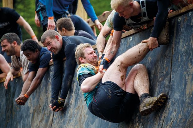 people helping each other to climb wall