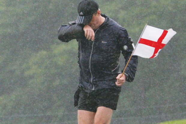 Man soaking wet as he runs through Wiltshire holding a St Georges Flag. Man soaking wet as he runs through Wiltshire holding a St Georges Flag.