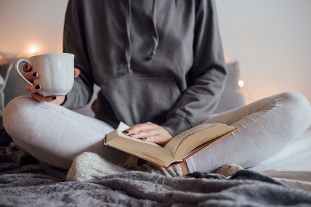 Woman reading book and drinking tea on bed Woman reading book and drinking tea on bed