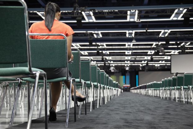 Woman sitting alone in empty conference centre Woman sitting alone in empty conference centre