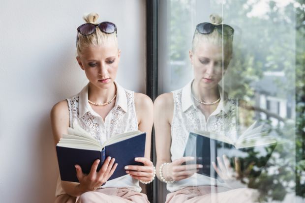 A woman reads a book on a window bench, with a reflection of her doing so in the window, illustrating duplicate publication A woman reads a book on a window bench, with a reflection of her doing so in the window, illustrating duplicate publication reading a book