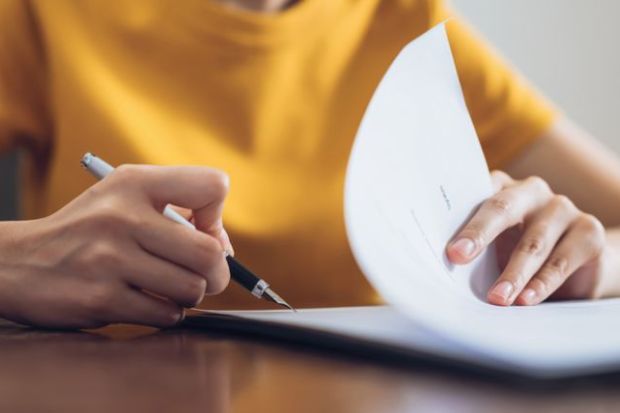 Woman signing document and hand holding pen putting signature at paper