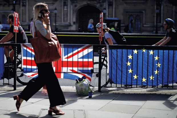 Woman walking past UK and EU flags Woman walking past UK and EU flags