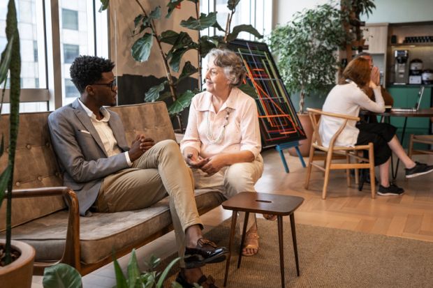 Young black university student being mentored by a mature woman in the workplace, illustrating that work placements can improve graduate employability.