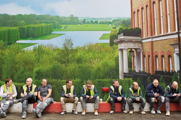 Workmen sit in front of hoarding depicting English country house and grounds Workmen sit in front of hoarding depicting English country house and grounds