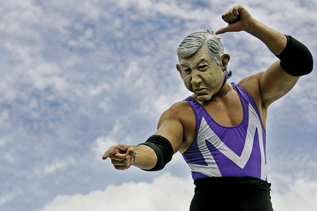 A wrestler in a mask points at something A wrestler in a mask points at something