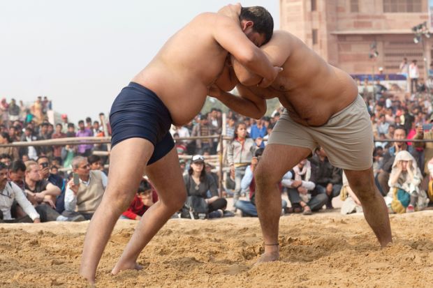 Wrestlers locked together symbolising pushback on university boards