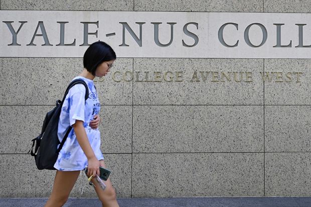 A student walking past signage for the Yale-NUS College in Singapore