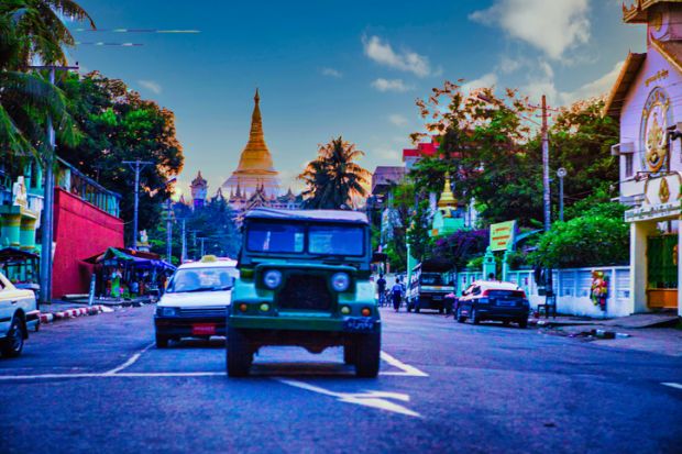 Yangon, Myanmar - December 02 2012  a military jeep on street of Yangon Myanmar and a Pagoda in the background